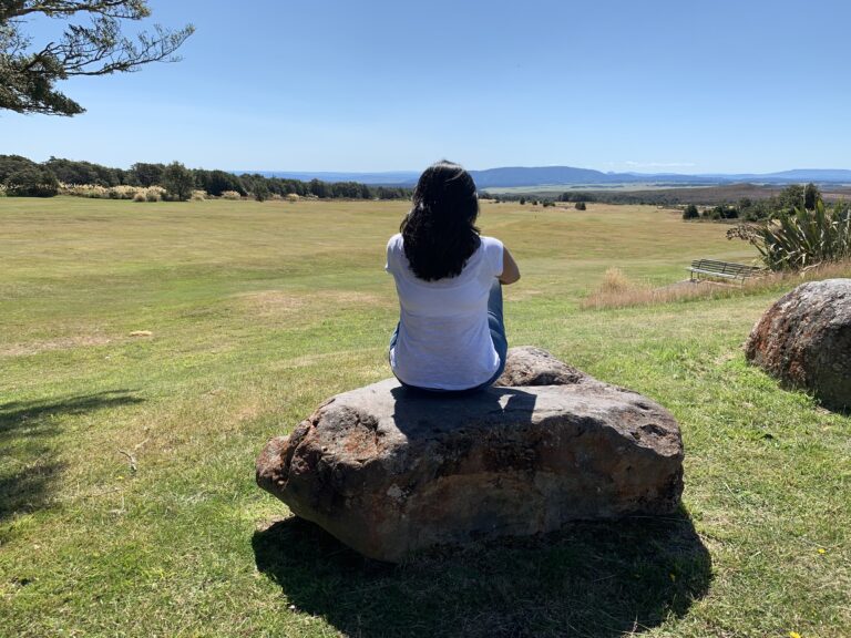 A person sitting alone in a grassy field, representing self-reflection and emotional distance.